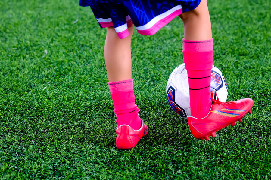 Child plays soccer on artificial turf