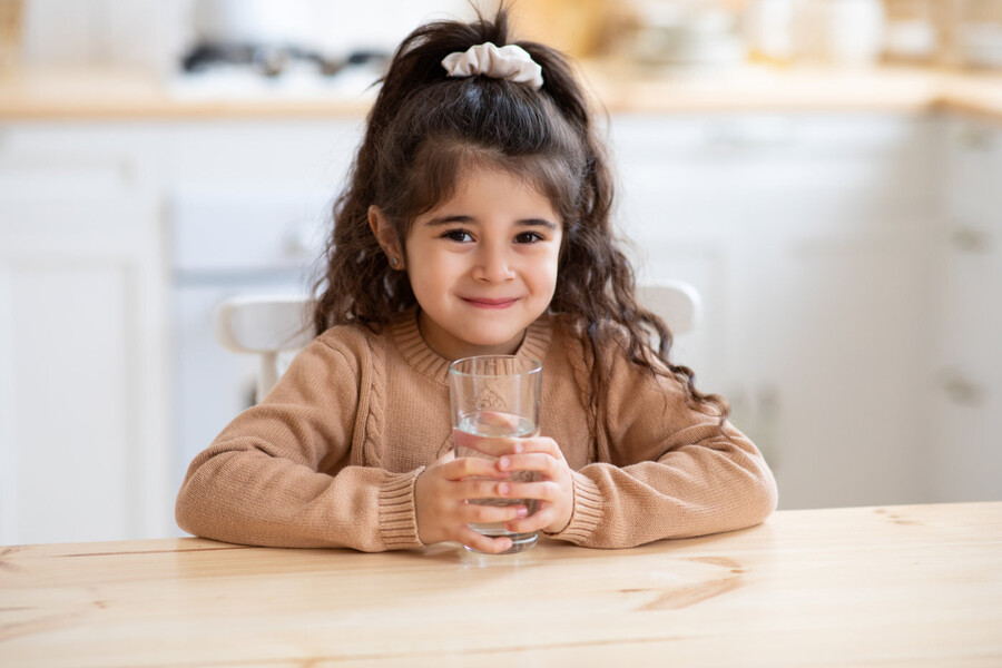 little girl holding glass of water