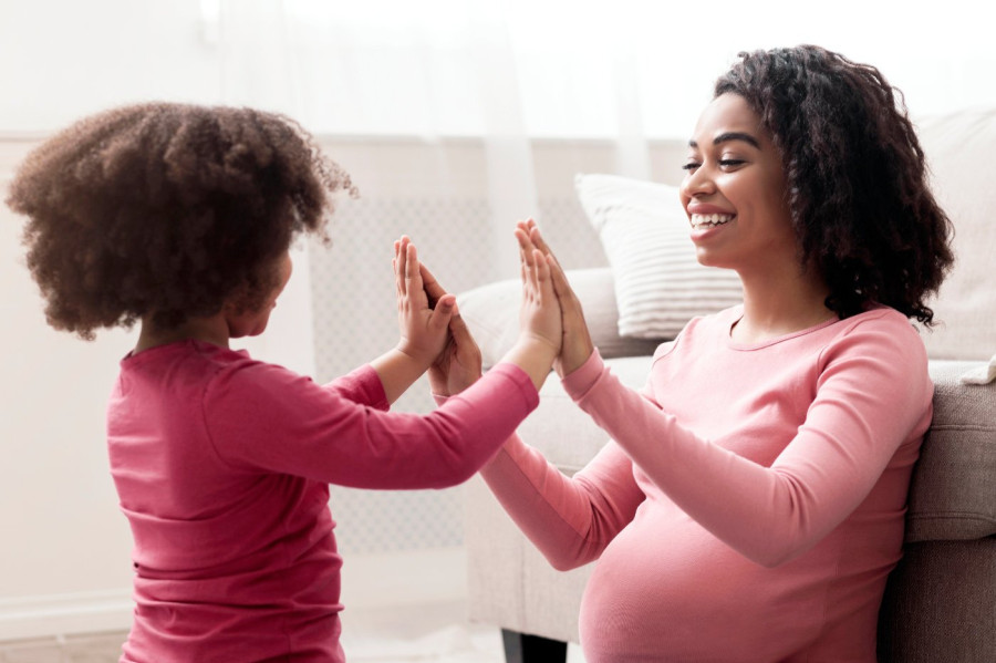 Pregnant woman and child touching hands
