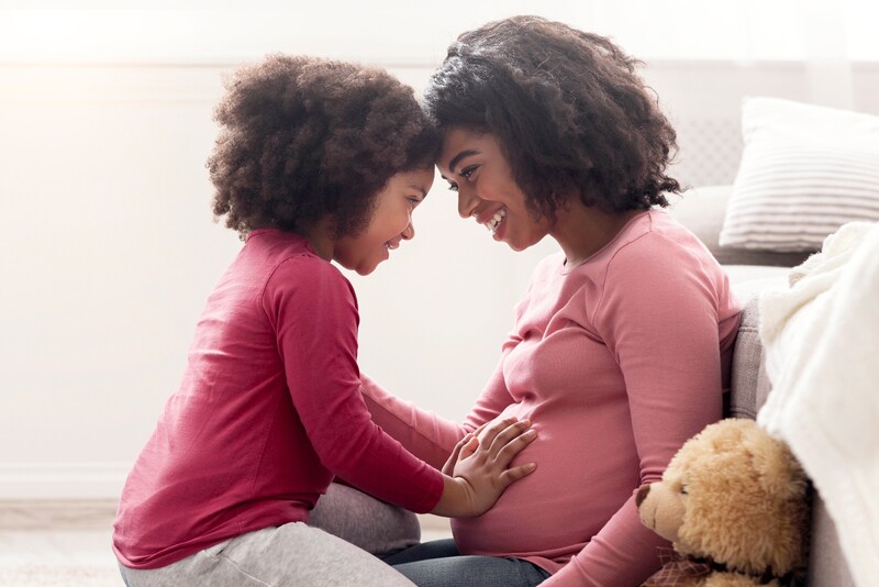 Happy Pregnant Woman And Her Daughter At Home
