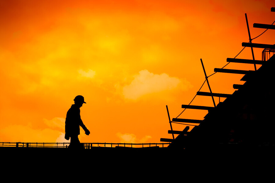 silhouette of construction worker in front or orange sky