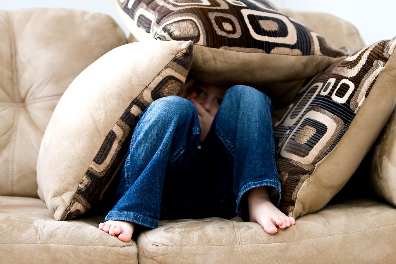 Child on couch surrounded by cushions